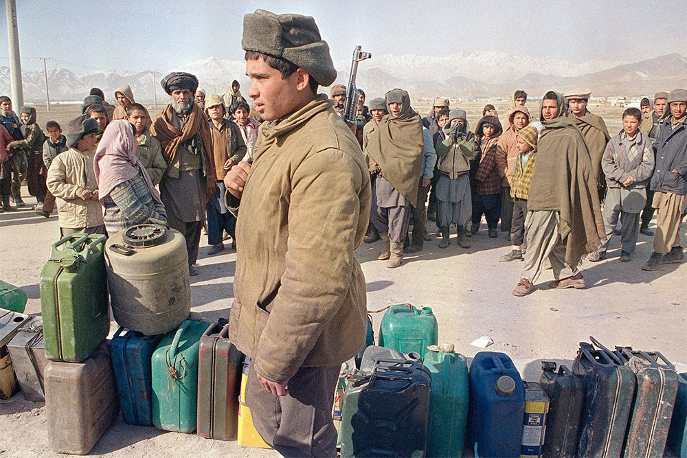 Афганский солдат охраняет очередь за топливом.