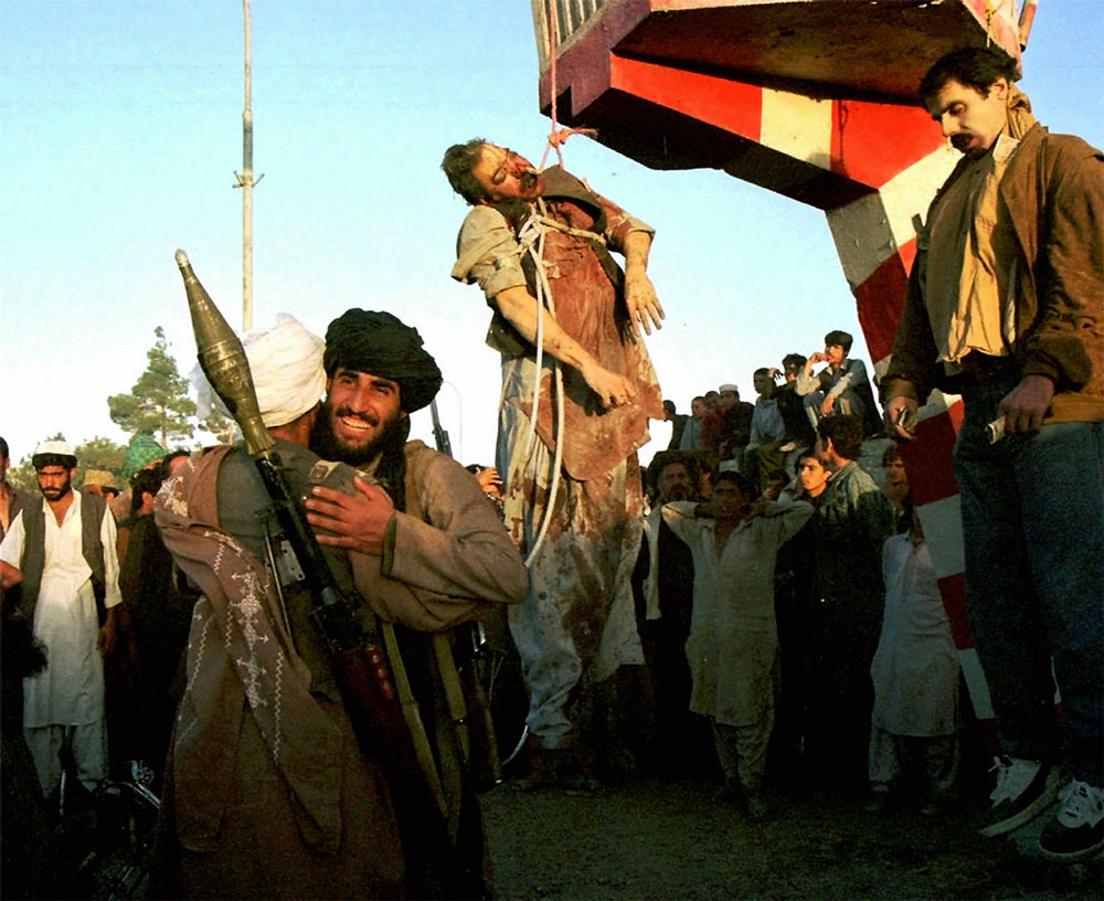 Талибы приветствуют друг друга на площади Кабула. Рядом на столбах висят тела президента Афганистана с 1987-го по 1992-й год Мохаммада Наджибуллы (справа) и его брата Ахмадзая. Последние четыре года жизни Наджибулла провел в стенах миссии ООН.